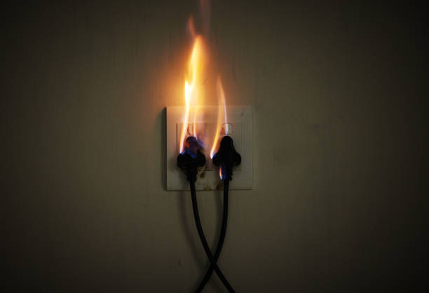 istock Wall, cables and electrical fire on a plug socket in studio on a dark background for safety. Danger, smoke and power with risk of flame on an outlet for electricity in the circuit of a home closeup 1820329735