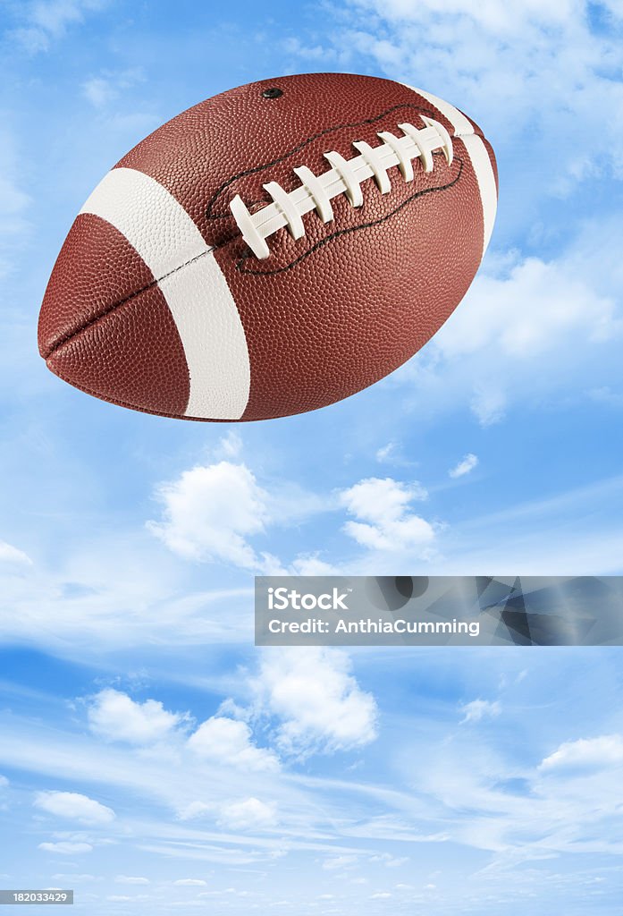 Pelle marrone football americano midair in blue sky - Foto stock royalty-free di Football americano