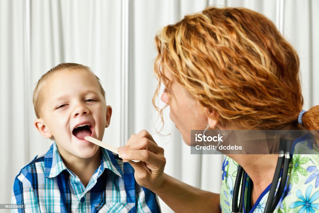 Médico usando sujetalenguas para verificar Young Boys de garganta - Foto de stock de Examen médico libre de derechos