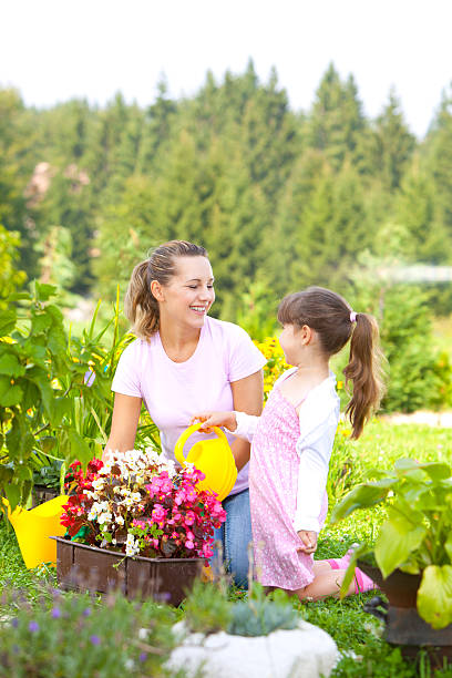istock Mother and daughter watering flowers 182033837