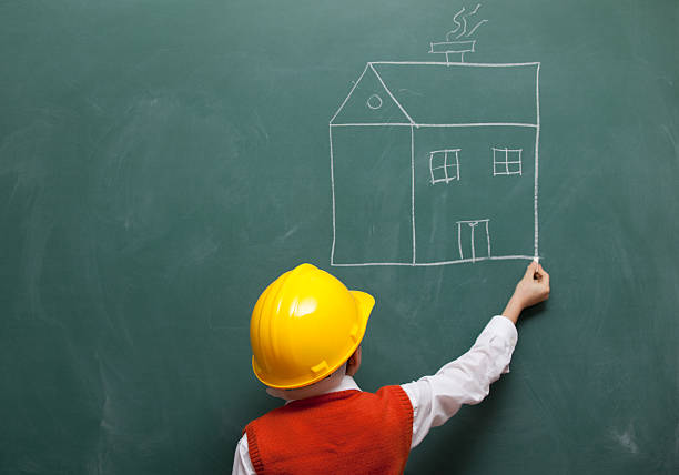 little ingegnere con casco disegno di una casa sulla lavagna - child building activity construction engineer foto e immagini stock