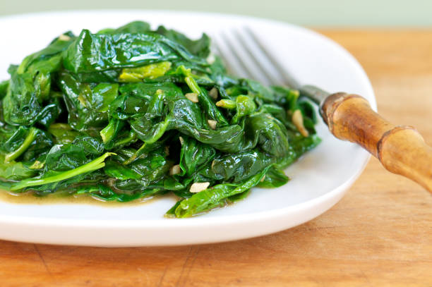 istock White Plate of Fresh Sauteed Spinach with Garlic on Wood 182035548