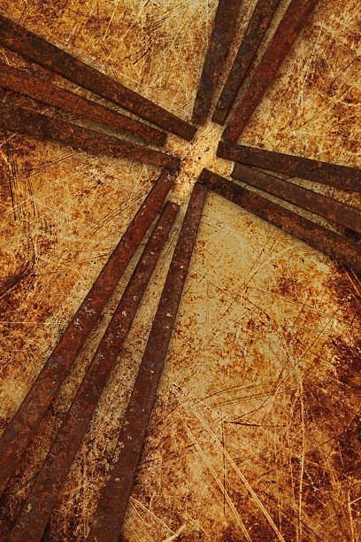 Cross of old square rusty iron nails on grungy scratched metal background forming a smaller cross in it's center.