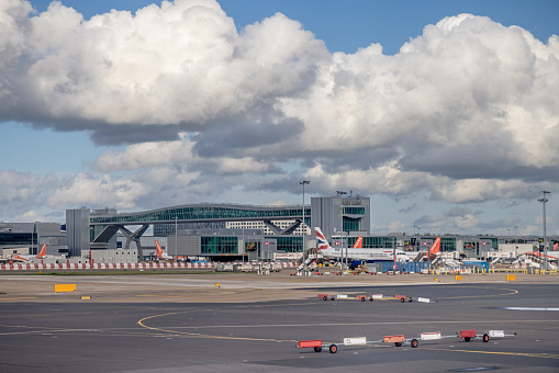 Commercial airplanes queued at airport gates with one on the runway.