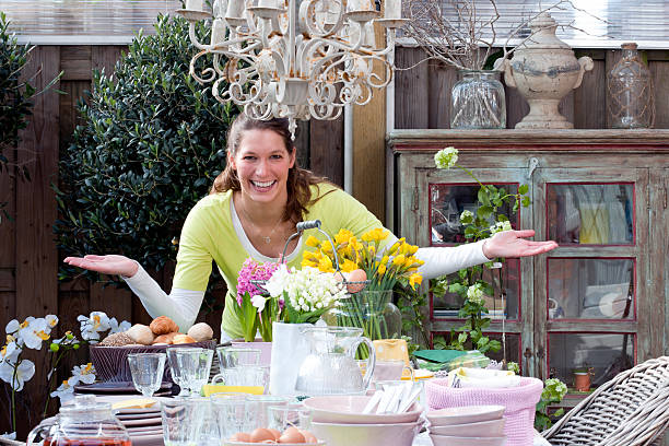 felice donna in piedi presso la prima colazione di pasqua tavolo da picnic - hyacinth flower vase daffodil foto e immagini stock