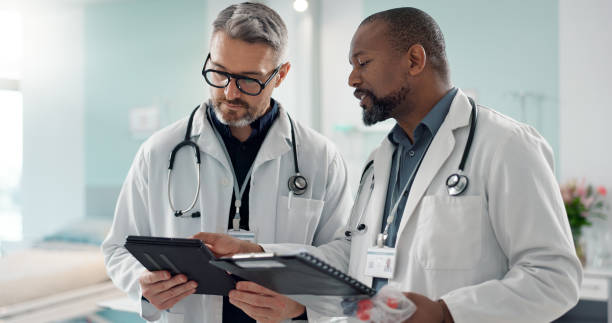 istock Doctors, men and tablet for team discussion, planning and advice with innovation, research or problem solving. Diversity, medical partnership and talk with notebook, digital touchscreen and report 1820379327