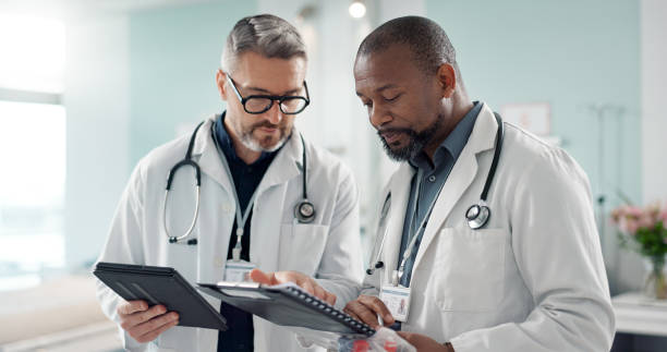 istock Doctors, men and tablet for team discussion, planning and advice with innovation, research or problem solving. Diversity, medical partnership and talk with notebook, digital touchscreen and report 1820379332