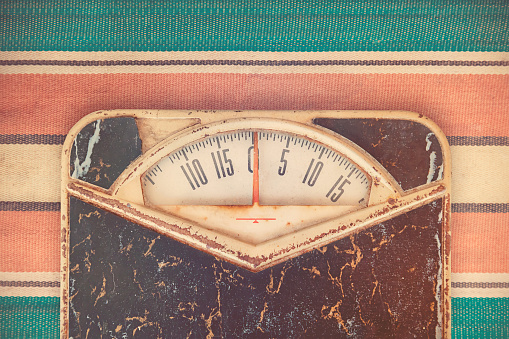 Retro styled image of a vintage weight scale on top of a colorful seventies rug