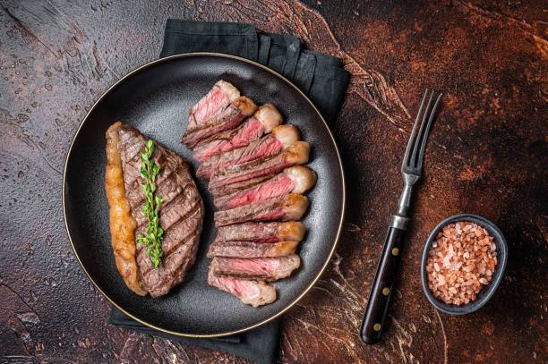 istock Sliced grilled medium rare Top sirloin beef steak on a plate. Dark background. Top view 1820382289