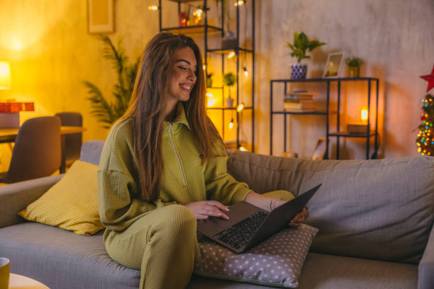 istock Beautiful woman sitting on the sofa while using laptop at home 1820383444
