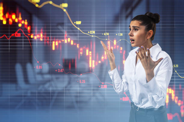istock Stressed young businesswoman with downward red candlestick forex chart with grid and index on blurry office interior background. Crisis, falling stock market and recession concept. Double exposure. 1820387452