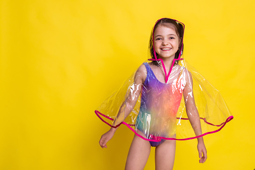 Chic protection, child girl dazzles in transparent raincoat and colorful swimsuit with copy space for logo or brand