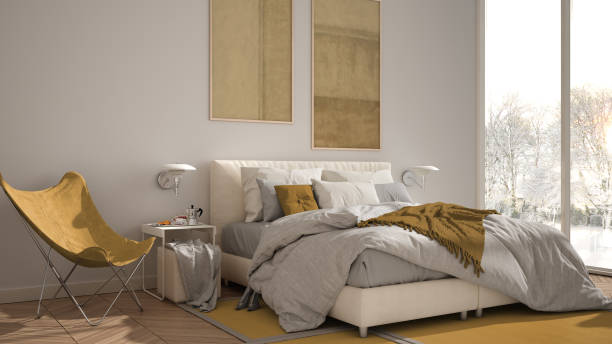 istock Modern yellow colored minimalist bedroom, bed with pillows and blankets, parquet, bedside tables and carpet. Panoramic window with winter panorama with trees and snow, interior design 1820401516