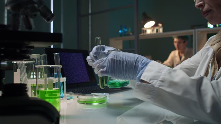 Female Chemist Mixing Blue and Green Liquid in Lab