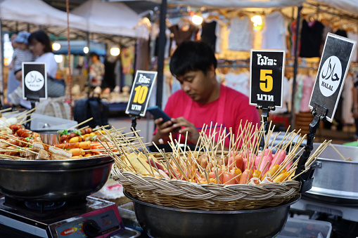 Phuket, Thailand - November 18, 2023: Thai man selling meat snacks at night market for tourists