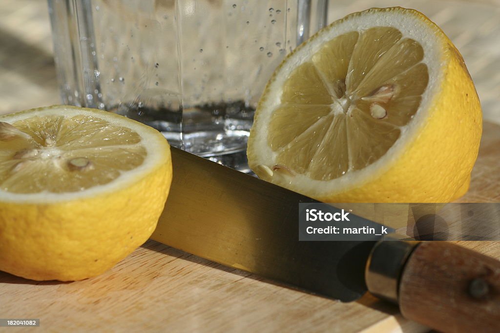 Cut Lemon "Cut Lemon on a cutting board, a glass of sparkling table water in the background" Boarded Up Stock Photo