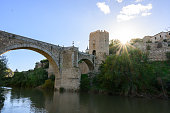 Back lit Alcantara Bridge (or Puente de Alcántara) and the skyline of Toledo