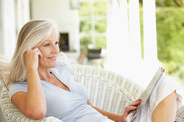 istock Senior woman in sofa reading a magazine outside 182041401