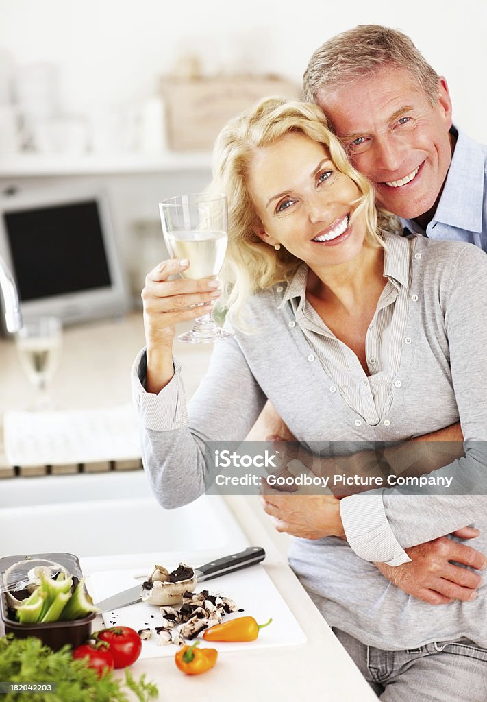 Mujer con copa de vino mientras que hombre Abrazos su desde atrás - Foto de stock de Cocinar libre de derechos