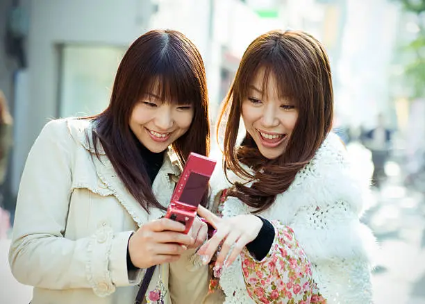 Friends looking at mobile phone in urban setting.