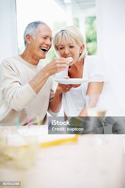 Cheerful Senior Man Feeding Mature Woman A Piece Of Cake Stock Photo - Download Image Now