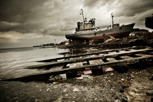 Commercial ship on the abandoned dock. Crisis in shipping industry. Desaturated and toned image.More grunge and destroyed buildings  in this lightbox