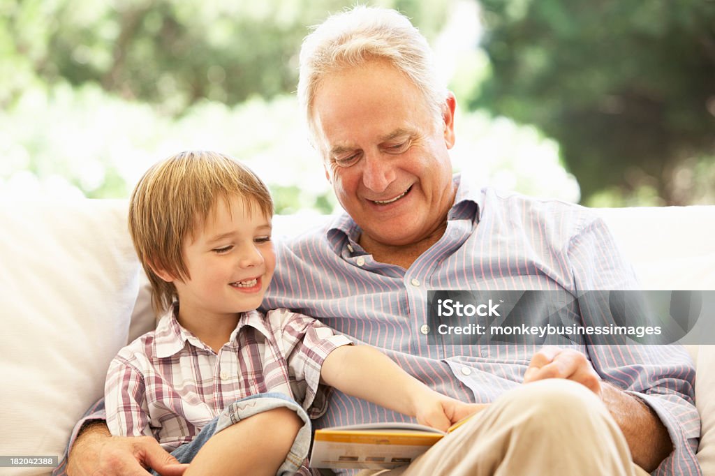 Abuelo con nieto lectura en SOFÁ - Foto de stock de Abuelo libre de derechos