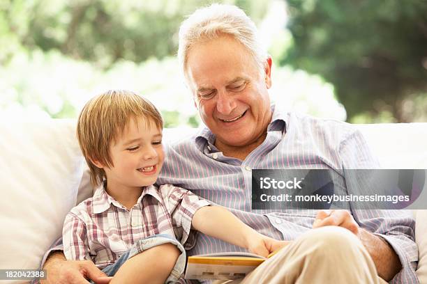 Abuelo Con Nieto Lectura En Sofá Foto de stock y más banco de imágenes de Abuelo - Abuelo, Abuelos, Niño