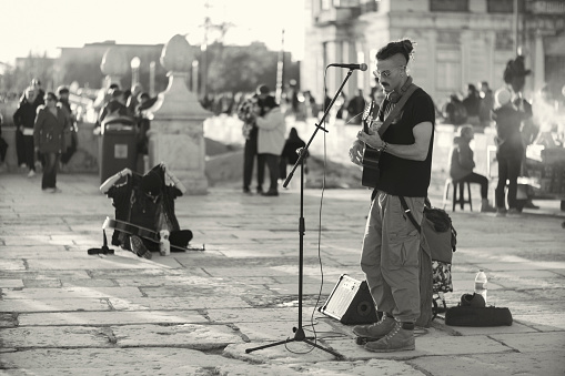 Lisbon, Portugal - December 17, 2022: A street musician performs by the Tagus River in Lisbon downtown.