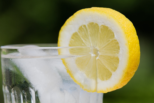 A glass of ice water with a lemon slice.