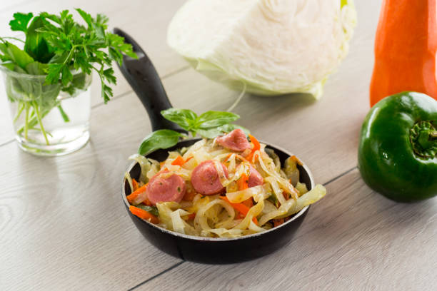 cooked fried cabbage with vegetables and sausages stock photo