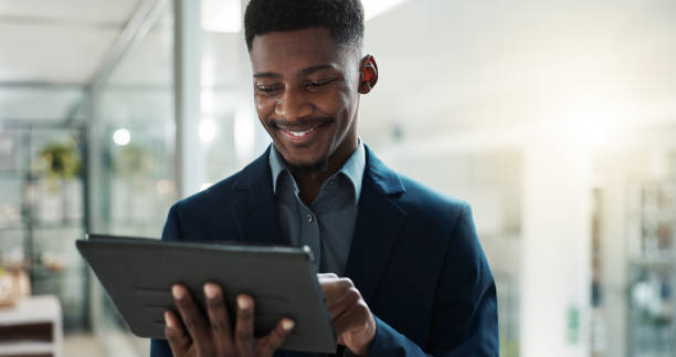 istock Tablet, networking and businessman in the office typing a message on the internet or mobile app. Digital technology, chatting and African male lawyer scroll on social media or website in workplace. 1820446223