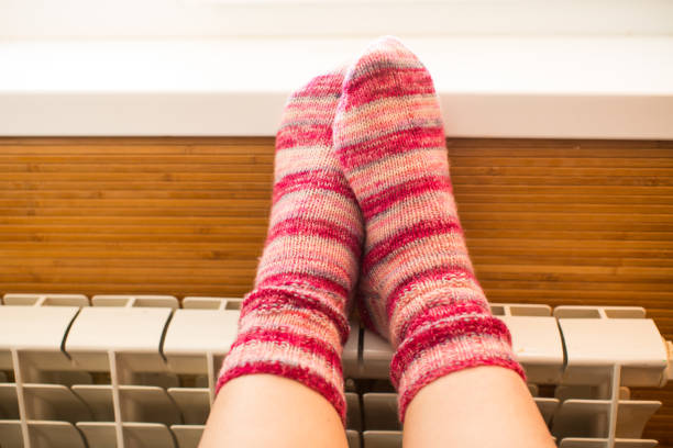 istock Feet in warm winter socks warm up on the radiator. 1820475255