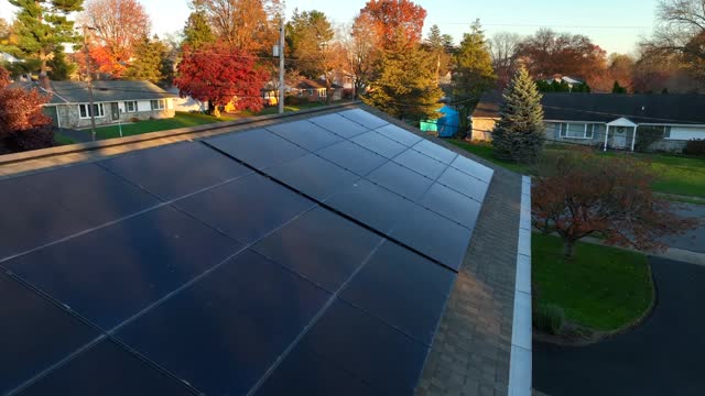 Solar panels on American home. Aerial close up flyover of black array during autumn sunset.