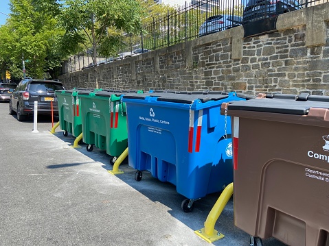 New York, NY USA - August 20, 2023 : A row of new large plastic curbside recycling containers, including ones for compost, metal, glass, plastic, cartons, paper and cardboard, from the NYC Department of Sanitation installed in front of A. Philip Randolph Campus High School in Harlem, New York City