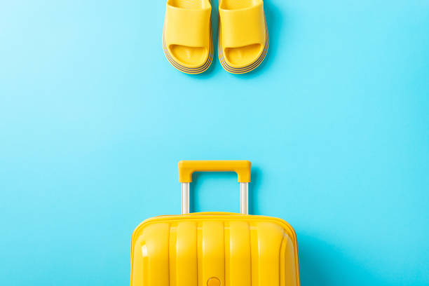 istock Take a break with a travel mindset. Top shot featuring a yellow suitcase, and rubber flip-flops on a lively blue surface. Advertise your travel deals effectively 1820492058