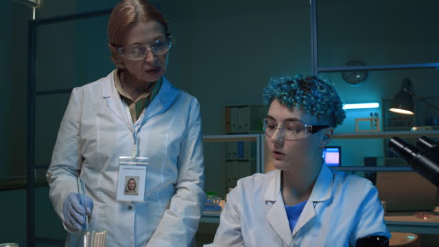 Two Female Scientists Discussing Liquid Samples in Chemistry Lab