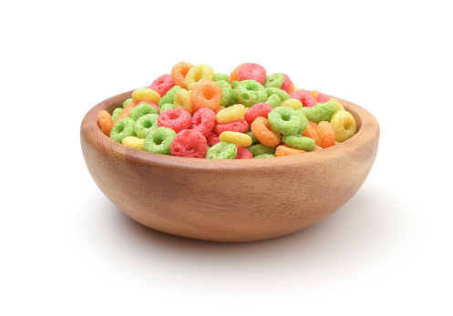 Multi-colored breakfast cereals in a wooden bowl isolated on white.