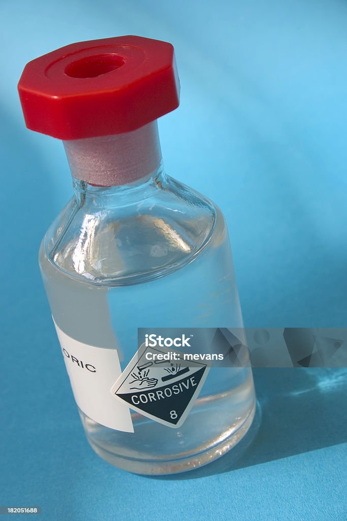 Corrosive A bottle of Hydrochloric acid on a blue background. Label Stock Photo