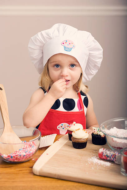 istock Cupcake Decorating by Little Girl in Chef's Hat and Apron 182051781