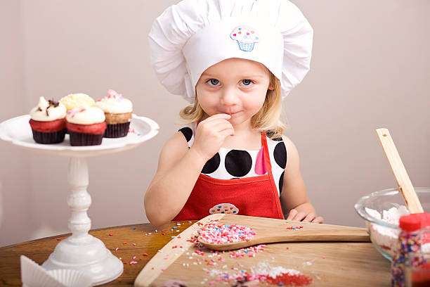 istock Cupcake Decorating by Little Girl in Chef's Hat and Apron 182052450