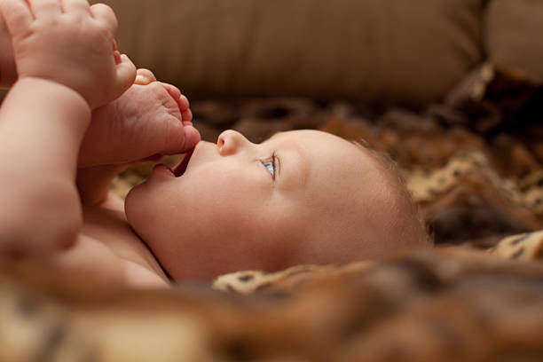 Baby boy face sucking feet mouth stock photo