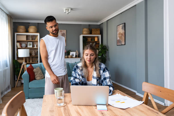 istock Young freelance woman remote working at home on laptop computer with boyfriend support. Business couple small online company owners research on internet, checking global market demand situation 1820537096