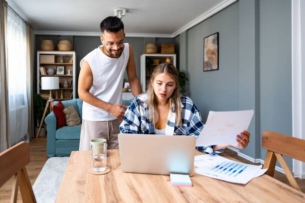 istock Young freelance woman remote working at home on laptop computer with boyfriend support. Business couple small online company owners research on internet, checking global market demand situation 1820537101