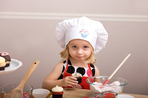 istock Cupcake Decorating by Little Girl in Chef's Hat and Apron 182053759