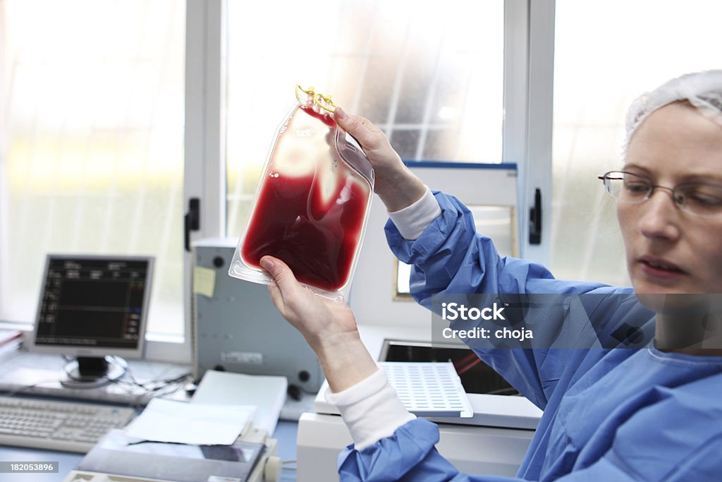 Medico con tuta hazmat sta controllando una sacca di sangue - Foto stock royalty-free di Composizione orizzontale