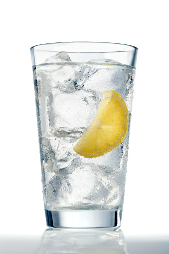 A glass of refreshing ice cold water with a lemon wedge.