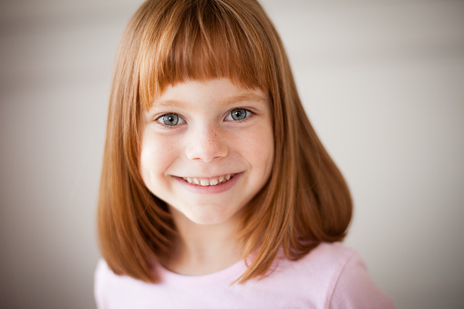 Color image of a cute, little red-haired girl showing off her new haircut. Shallow depth of field.