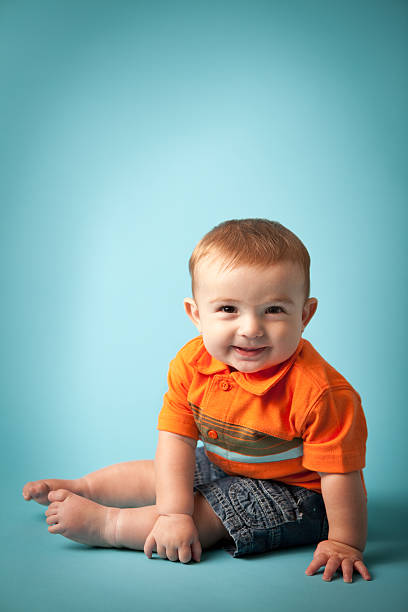 istock Smiling Baby Boy Sitting on Turquoise Background, With Copy Space 182054903