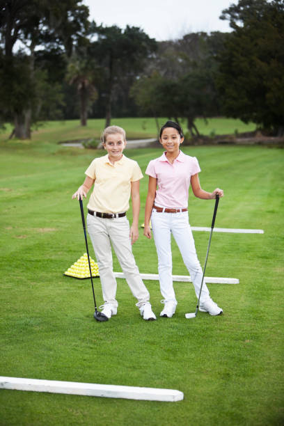 niñas de pie en un campo de práctica de golf - sc0529 fotografías e imágenes de stock